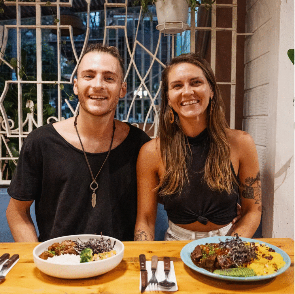 Turistas felices comiendo en el restaurante Auténtico en Medellín, sonriendo a cámara